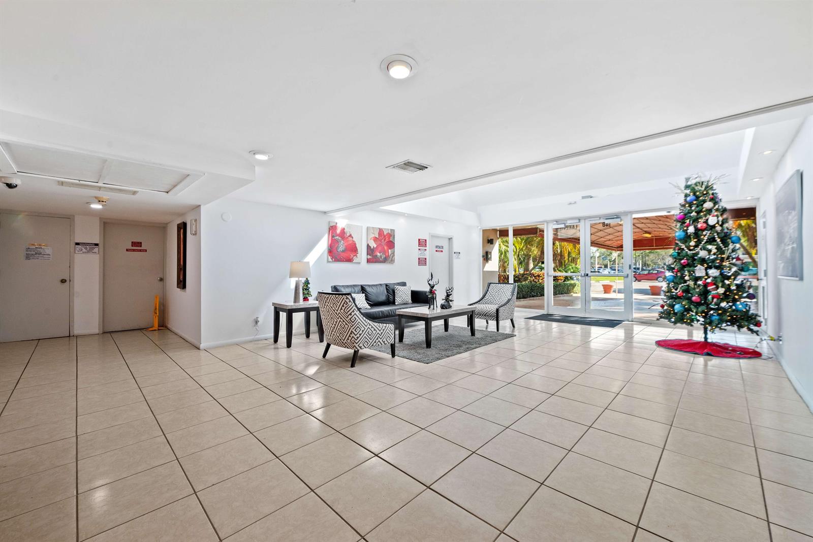 A tiled lobby features a seating area with a sofa, chairs, and a Christmas tree — 140 Lakeview Drive # 103, Weston FL 33326, WESTON, FL