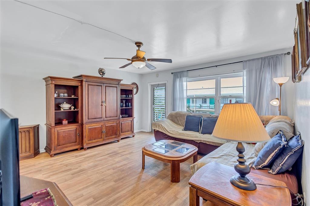 A living room features wood-look flooring, a large wooden entertainment center, and a sectional sofa — 5940 21ST STREET N UNIT 11, ST PETERSBURG, FL