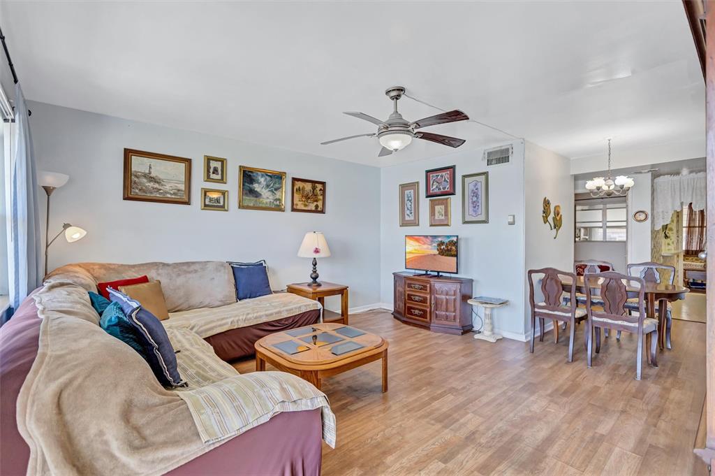 A living room with wood-look flooring, a sectional sofa, a television console, and a dining area — 5940 21ST STREET N UNIT 11, ST PETERSBURG, FL