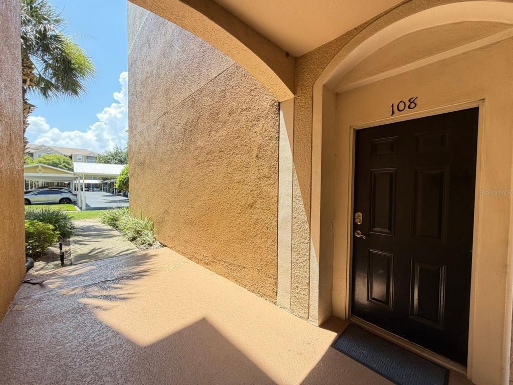 A dark brown front door with the number 108 sits under a covered entryway — 6466 CAVA ALTA DRIVE UNIT 108, ORLANDO, FL