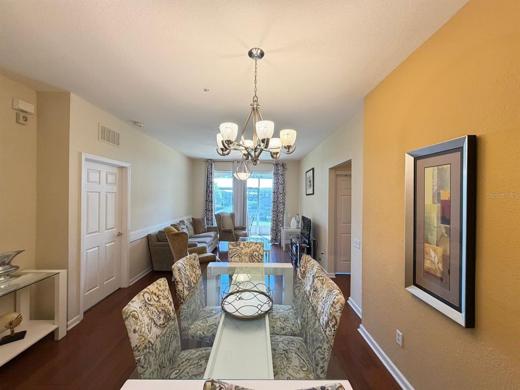 A dining area with a glass table and patterned chairs leads into a living room — 6466 CAVA ALTA DRIVE UNIT 108, ORLANDO, FL