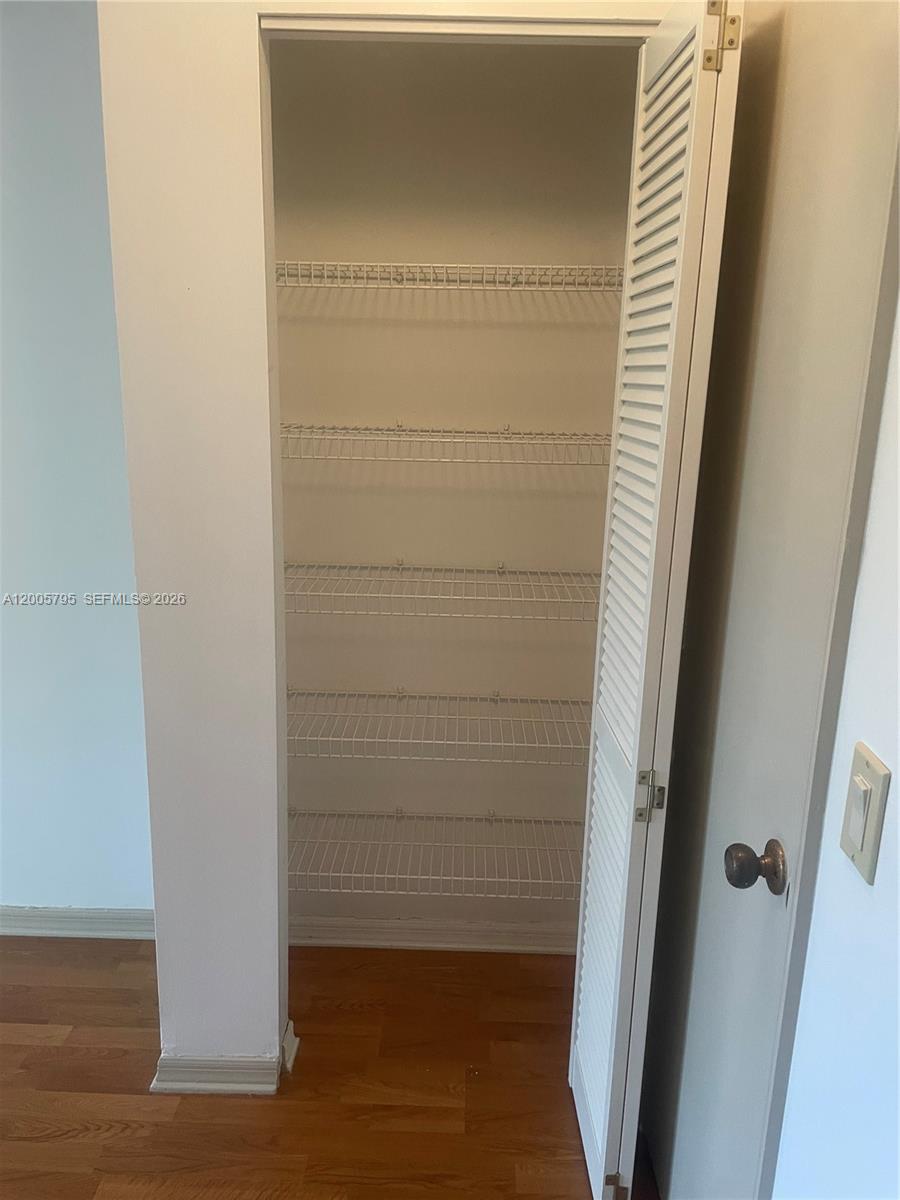 A closet with white wire shelving and a louvered door stands on a wood floor — 6553 SE Federal Hwy # 102, Stuart FL 34997, STUART, FL