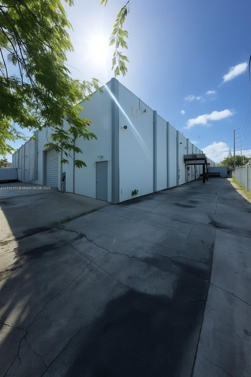 A white industrial warehouse building features a concrete driveway and a metal roll-up door — 4201 NW 37th Ct # 3728, Hialeah FL 33142, HIALEAH, FL