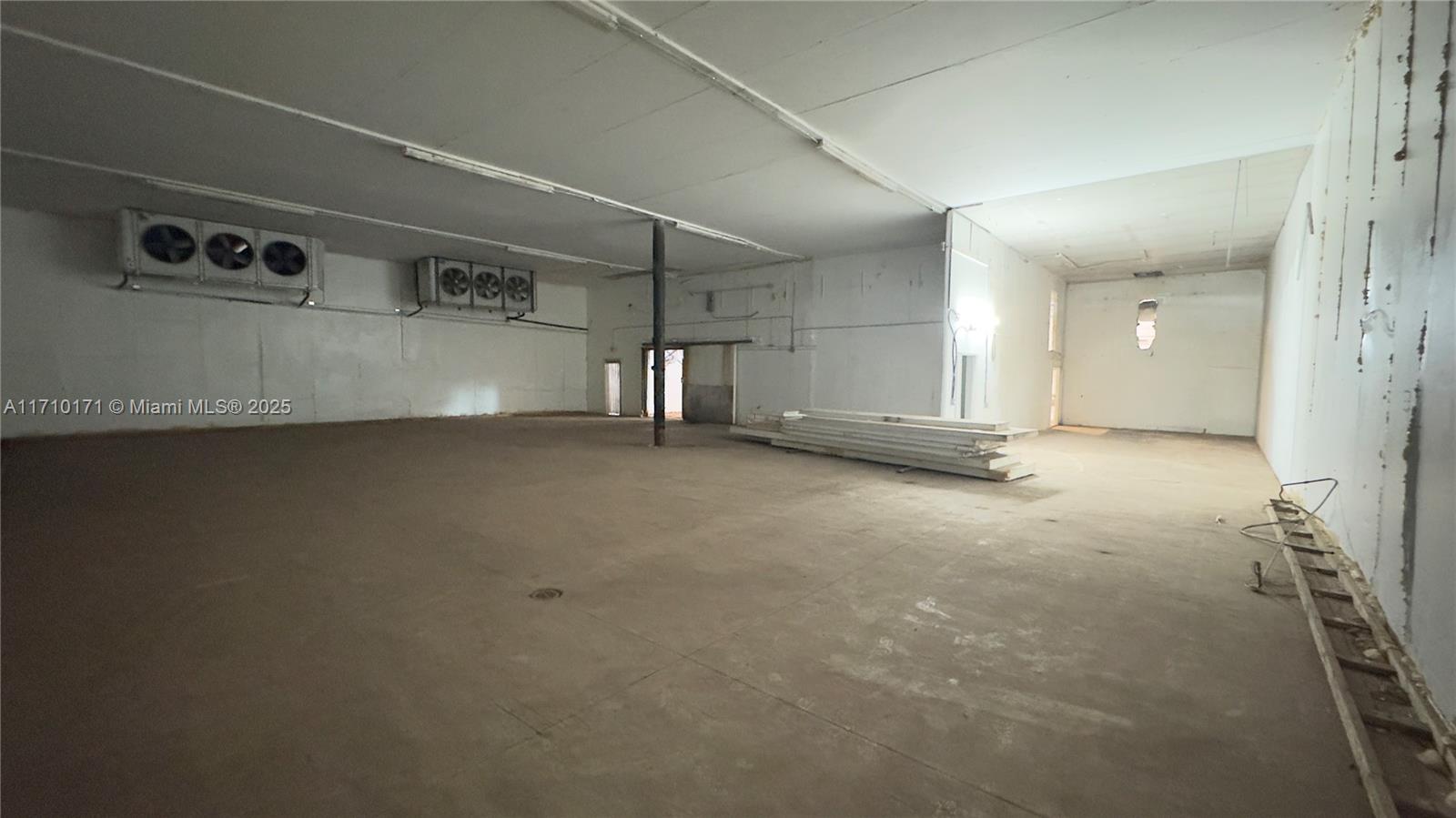 An empty commercial space features concrete floors, white walls, and two wall-mounted cooling units — 4201 NW 37th Ct # 3728, Hialeah FL 33142, HIALEAH, FL