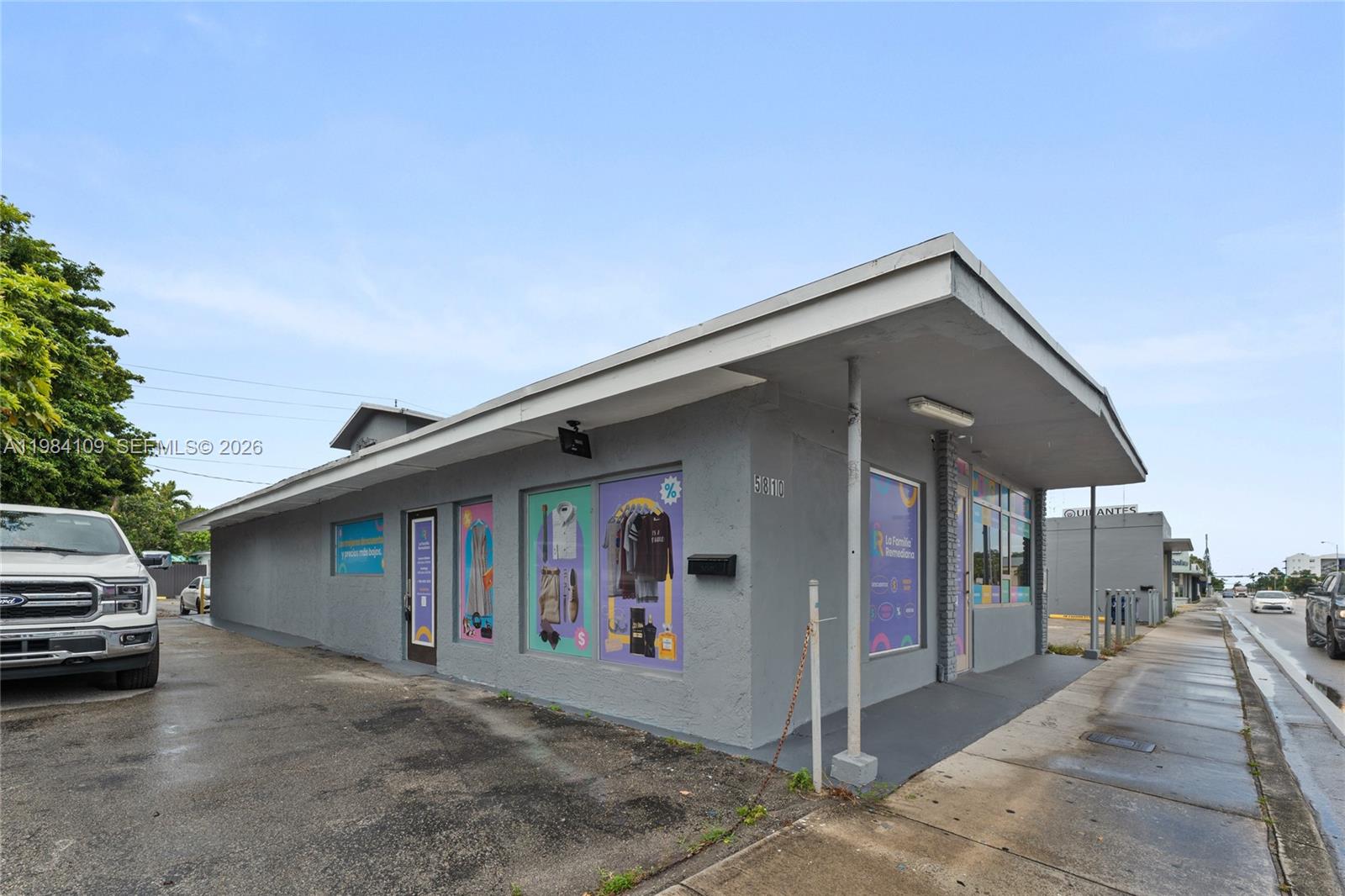 A single-story gray commercial building with large display windows sits along a street — 5810 W Flagler St # 5810, Miami FL 33144, MIAMI, FL