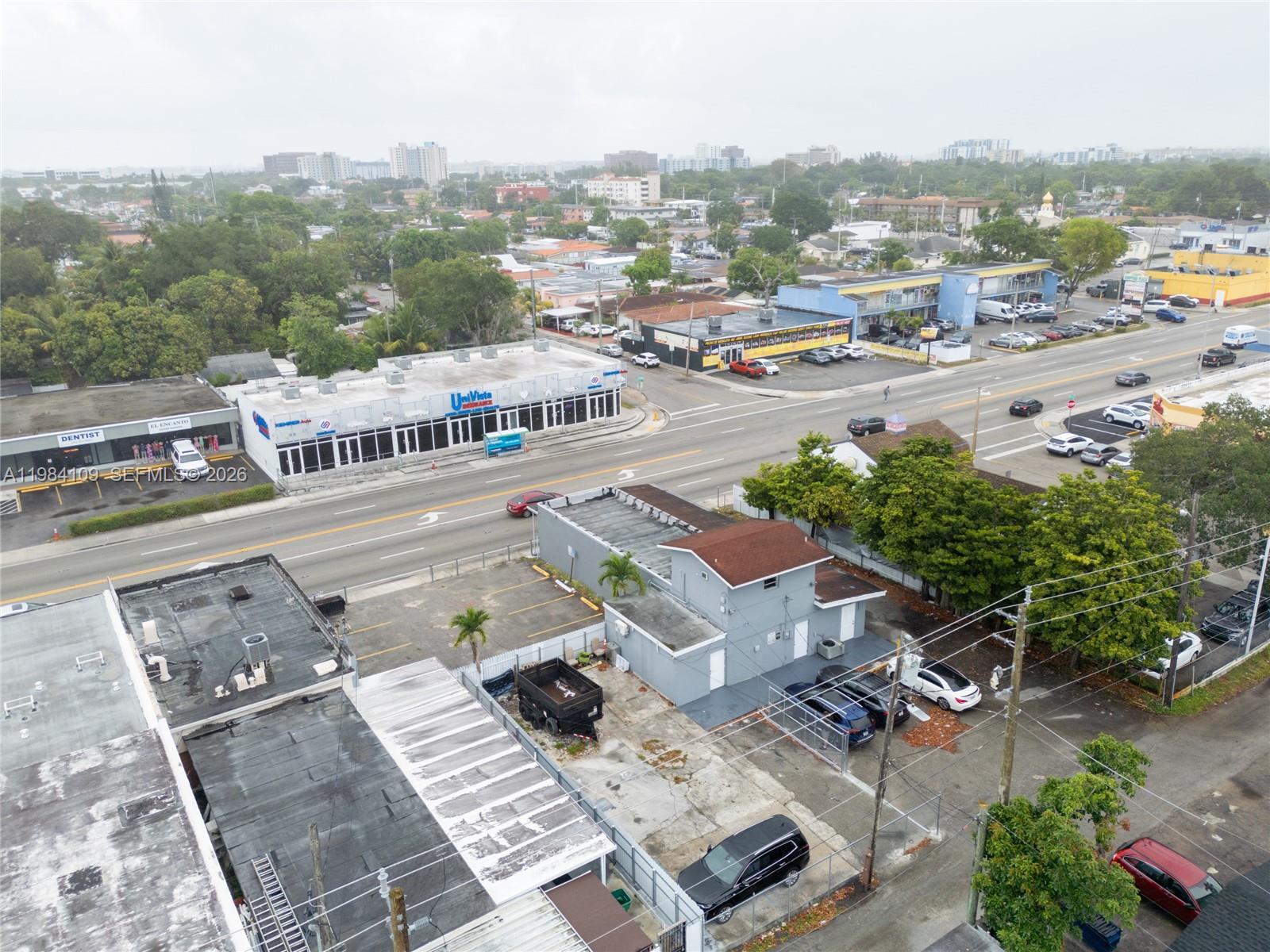An aerial view shows a commercial street with buildings, parking lots, and surrounding neighborhood trees — 5810 W Flagler St # 5810, Miami FL 33144, MIAMI, FL