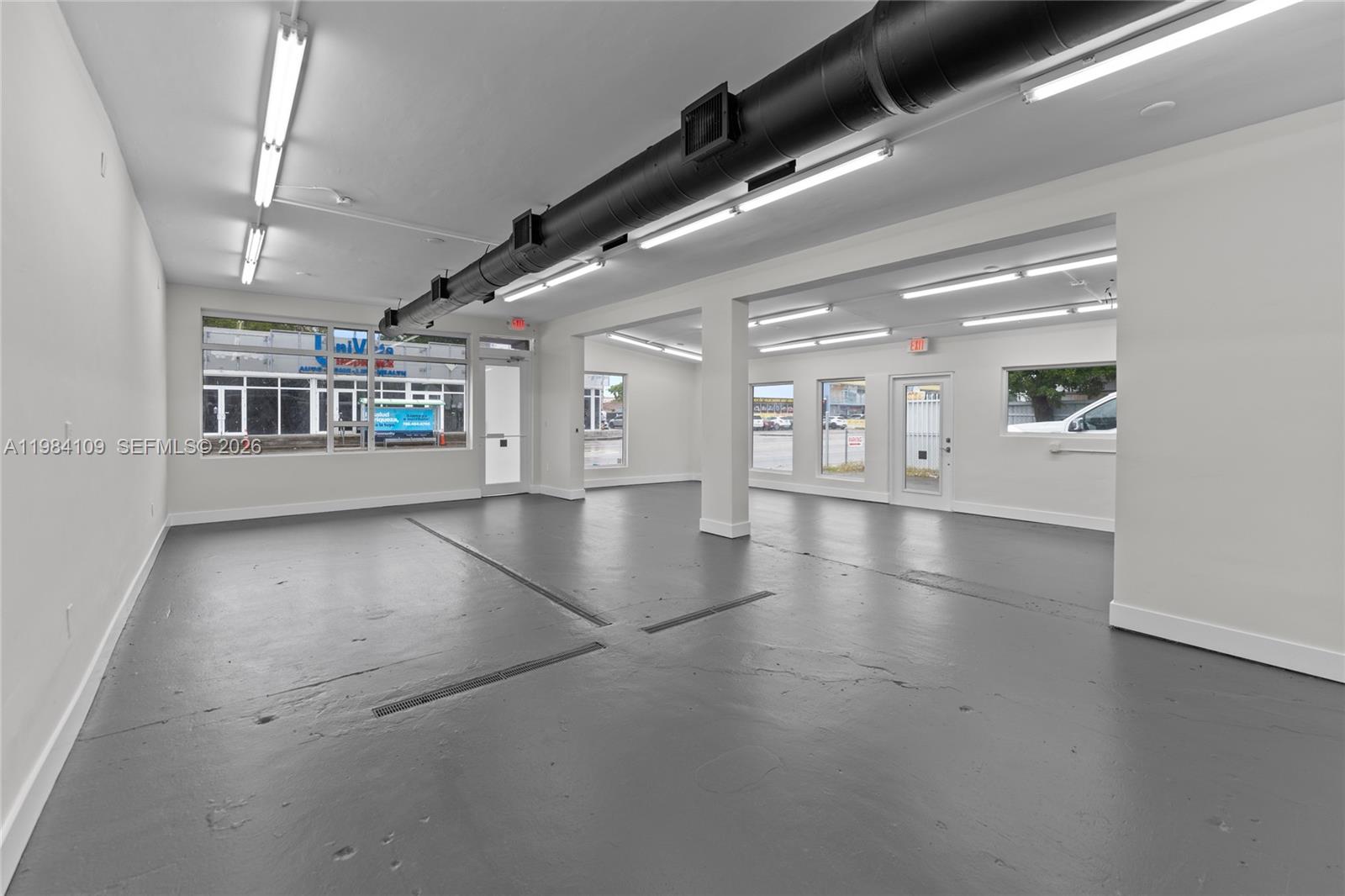 An open commercial space features gray painted floors, white walls, and exposed ceiling ductwork — 5810 W Flagler St # 5810, Miami FL 33144, MIAMI, FL