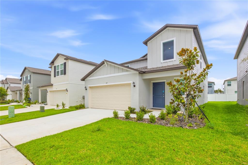 A two-story suburban house with a beige garage, blue front door, and green lawn — 641 BALD CYPRESS DRIVE, LAKELAND, FL
