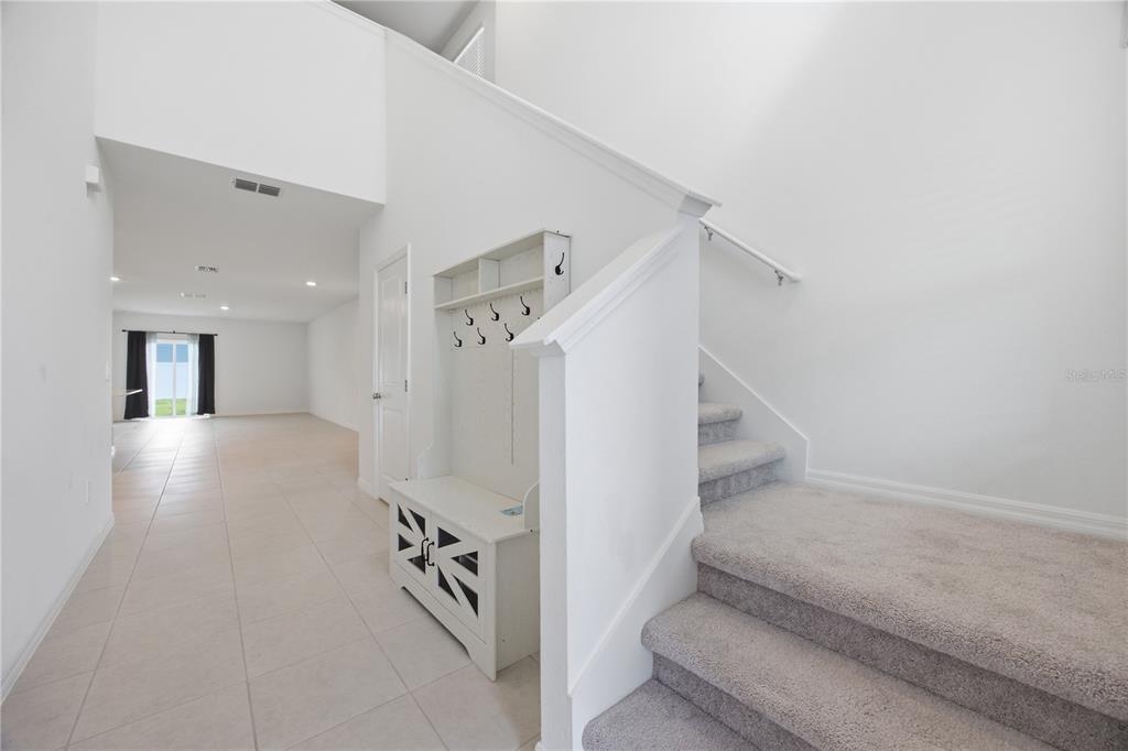 An entryway features a carpeted staircase, a white hall tree, and tile flooring — 641 BALD CYPRESS DRIVE, LAKELAND, FL