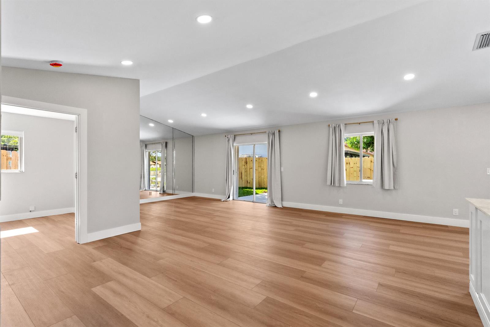 A spacious living room with light wood flooring, recessed lighting, mirrored walls, and sliding doors — 74 Vista Del Rio, Boynton Beach FL 33426, BOYNTON BEACH, FL