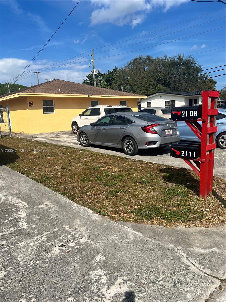 A yellow house with a driveway and a red mailbox post stands under a sky — 2111 NW 100th St # B, Miami FL 33147, MIAMI, FL