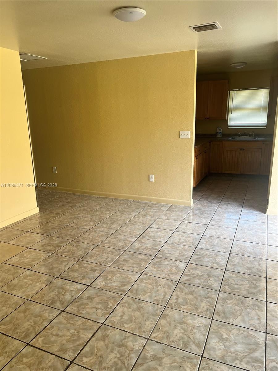 A tiled dining area opens into a kitchen with wooden cabinets and a window — 2111 NW 100th St # B, Miami FL 33147, MIAMI, FL