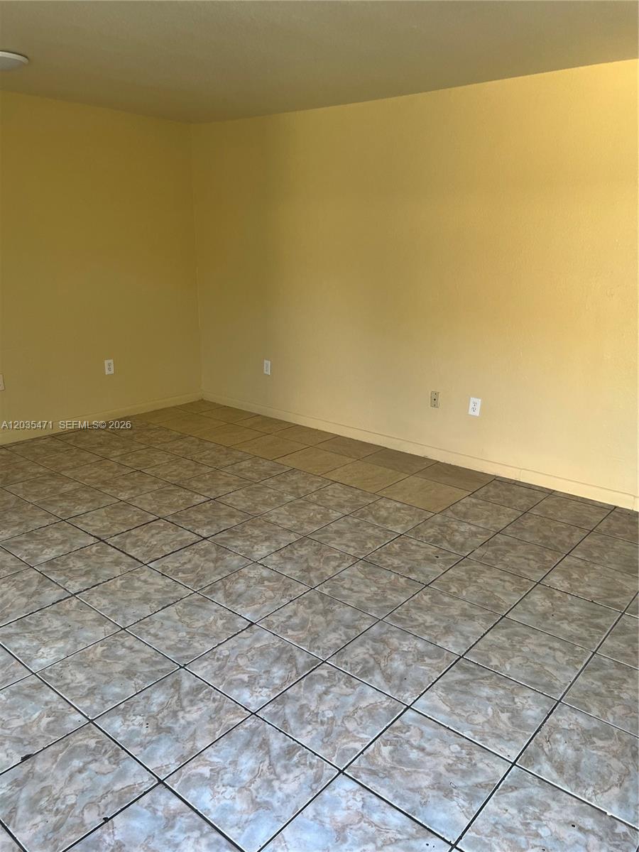 An empty room features light yellow walls and a floor covered in patterned tiles — 2111 NW 100th St # B, Miami FL 33147, MIAMI, FL