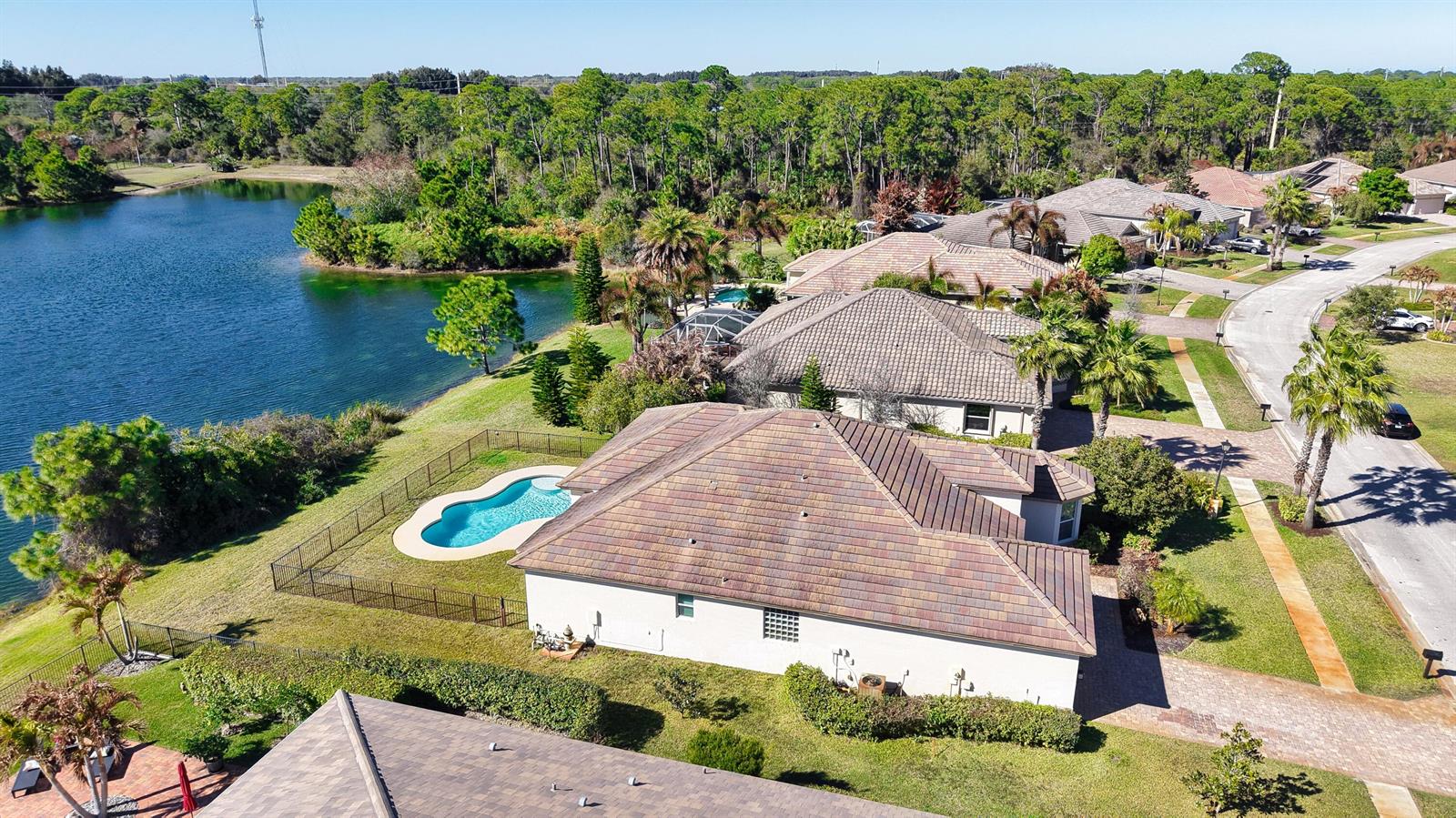 An aerial view shows a residential house with a pool and lakefront backyard — 7621 Fieldstone Ranch Square, Vero Beach FL 32967, VERO BEACH, FL