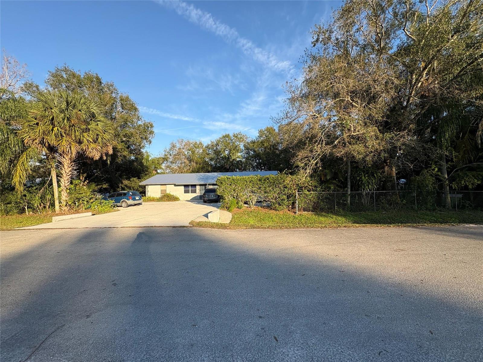 A single-story house with a metal roof sits behind a concrete driveway and trees — 540 NW 24th Avenue, Okeechobee FL 34972, OKEECHOBEE, FL