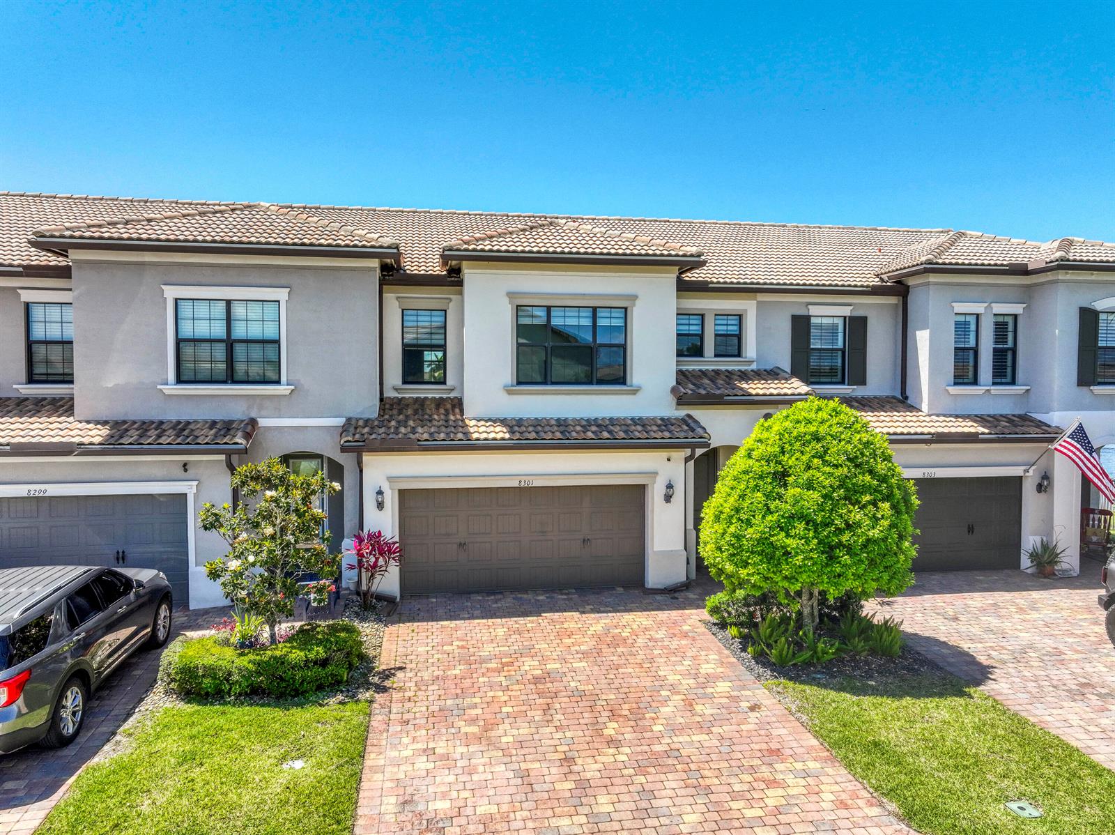 An exterior view of a multi-unit townhouse complex with brick driveways and tile roofs — 8301 Rearing Lane, Lake Worth FL 33467, LAKE WORTH, FL