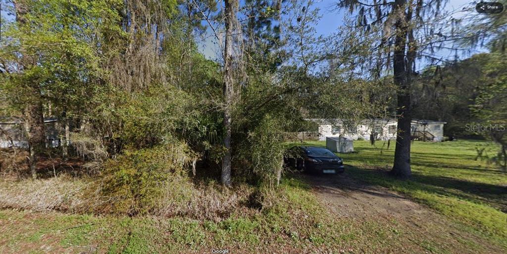 A dark car is parked on a dirt driveway in front of a wooded lot — R JONES ROAD, CALLAHAN, FL