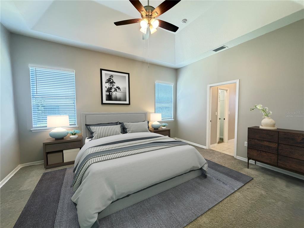 A bedroom features a tray ceiling, a ceiling fan, a bed, and a wooden dresser — 1751 SOUTHERN OAK LOOP, MINNEOLA, FL