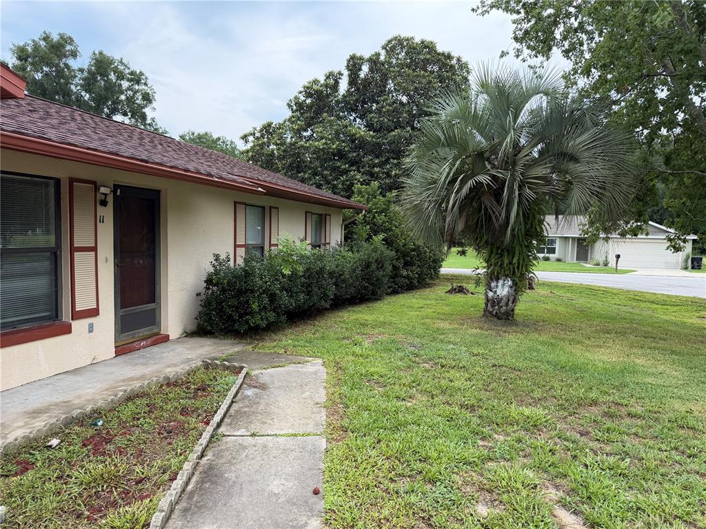A single-story house with a beige exterior, red trim, and a palm tree in the yard — 11 PINE CIRCLE LANE, OCALA, FL