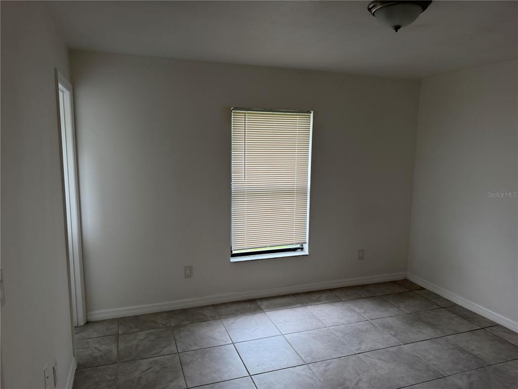 An empty room with white walls, a single window with blinds, and tiled flooring — 11 PINE CIRCLE LANE, OCALA, FL