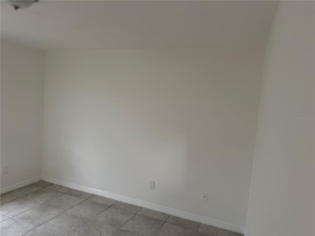 An empty room with white walls and gray tiled flooring — 11 PINE CIRCLE LANE, OCALA, FL