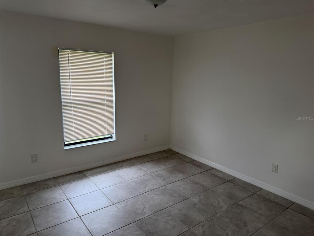 An empty room with white walls, a single window with blinds, and tiled flooring — 11 PINE CIRCLE LANE, OCALA, FL