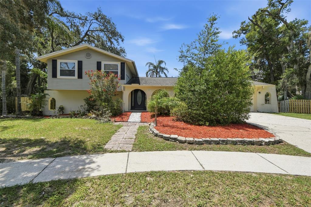A two-story house with light-colored siding and stucco features a front yard with landscaping — 1200 LAKE VALRICO LANE, VALRICO, FL