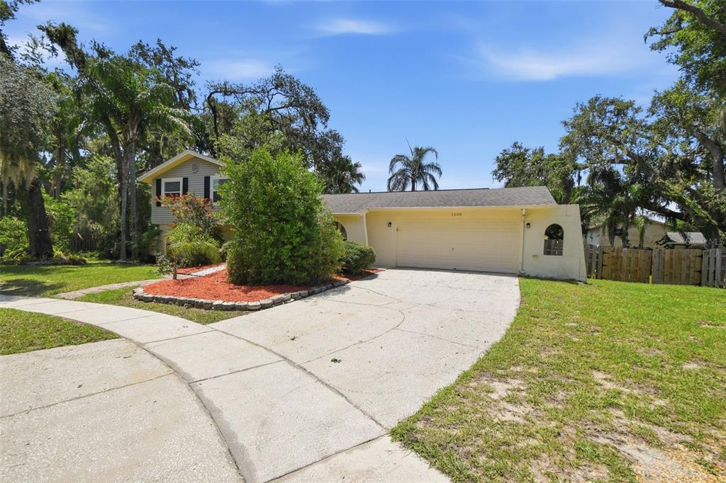 A two-story house with a beige exterior, a two-car garage, and a concrete driveway — 1200 LAKE VALRICO LANE, VALRICO, FL