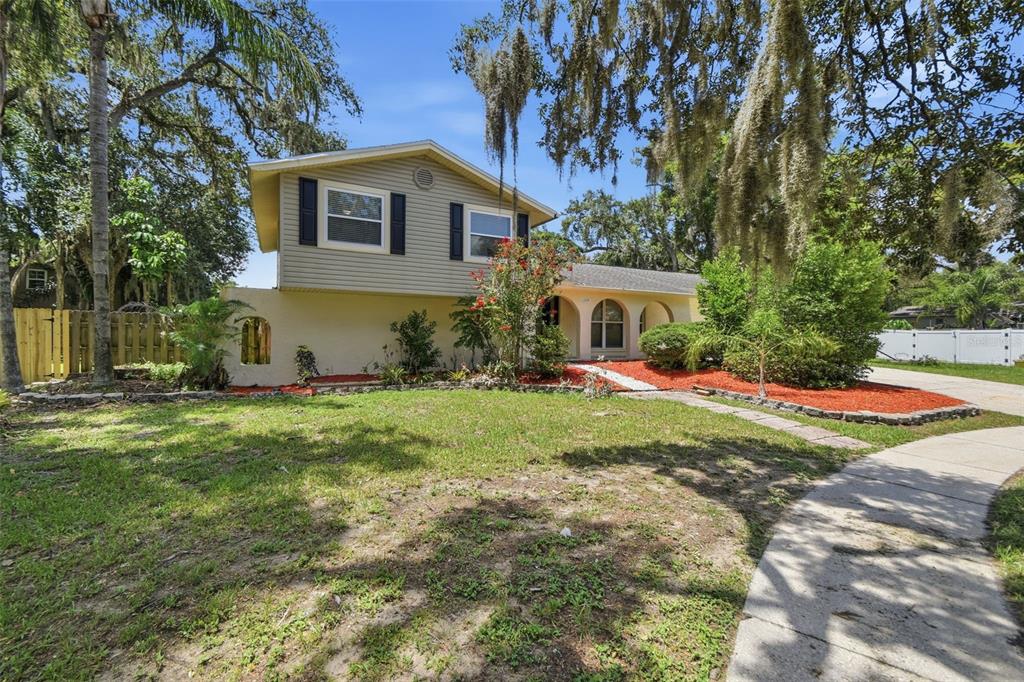 A two-story house with beige siding and a front yard under large oak trees — 1200 LAKE VALRICO LANE, VALRICO, FL