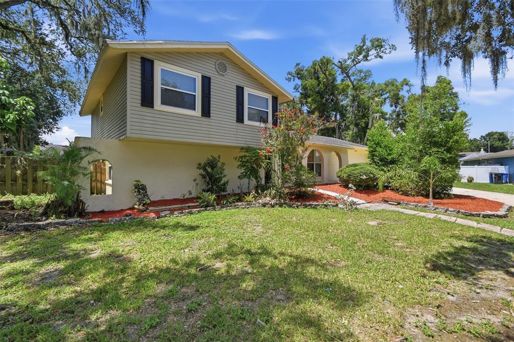A two-story house with light-colored siding and a stucco lower level sits on a lawn — 1200 LAKE VALRICO LANE, VALRICO, FL