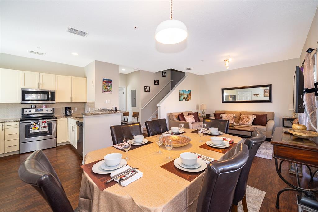 An open-concept kitchen, dining area, and living room featuring dark wood floors and neutral walls — 8913 W SHINE DRIVE, KISSIMMEE, FL