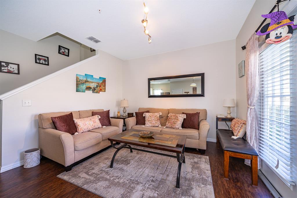 A living room features two beige sofas, a coffee table, and a large wall mirror — 8913 W SHINE DRIVE, KISSIMMEE, FL