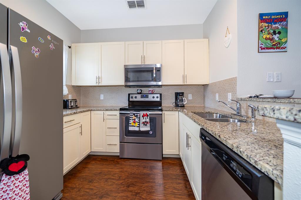 A kitchen features cream cabinets, granite countertops, stainless steel appliances, and wood-look flooring — 8913 W SHINE DRIVE, KISSIMMEE, FL