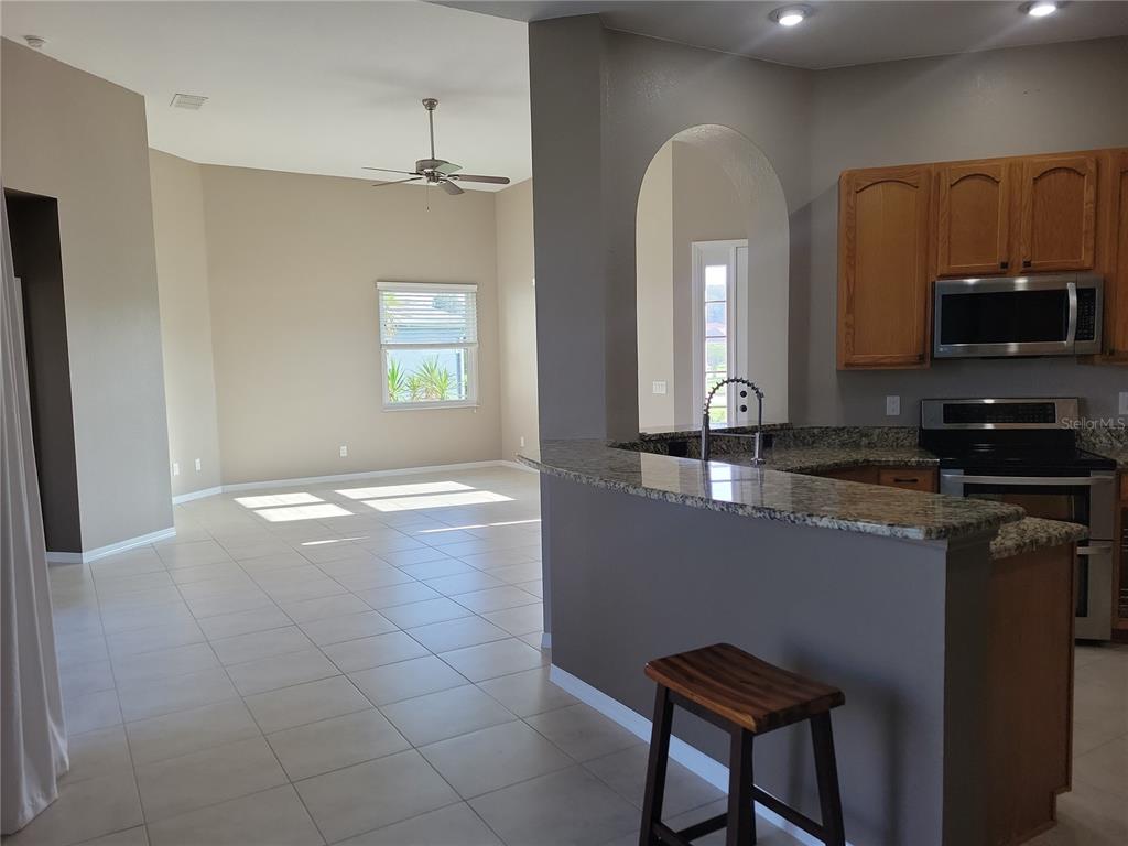 A tan house exterior features a red front door, a walkway, and a small porch — 11972 SE 176TH PLACE ROAD, SUMMERFIELD, FL