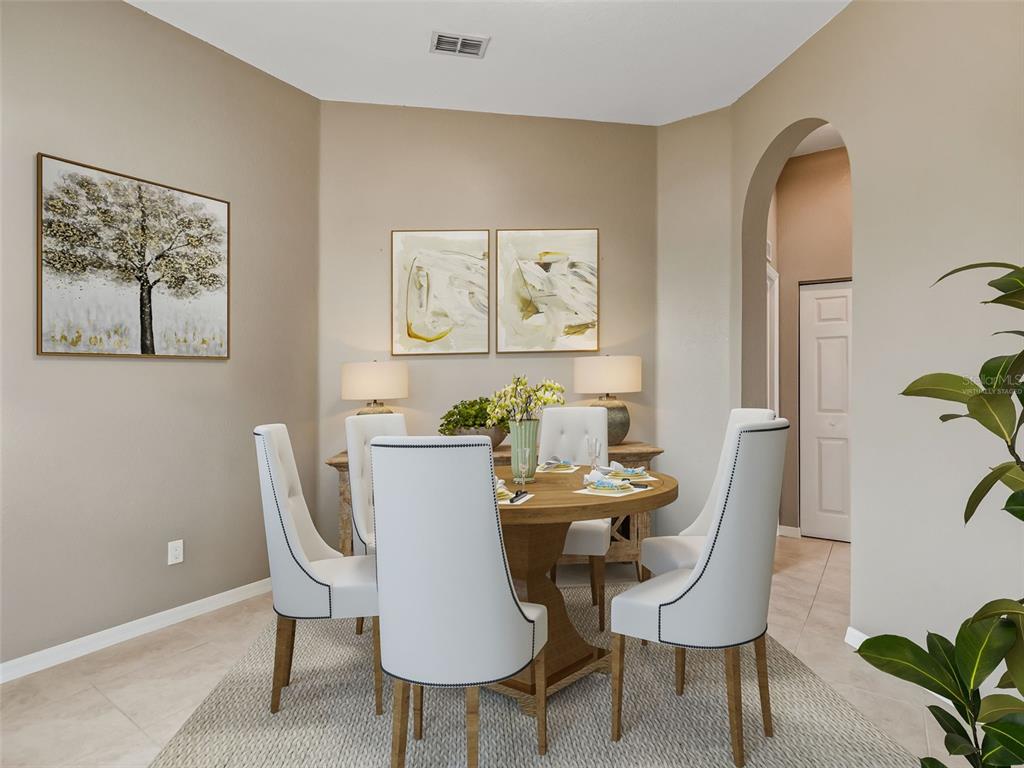 A dining room features a round wooden table, white upholstered chairs, and wall art — 11972 SE 176TH PLACE ROAD, SUMMERFIELD, FL