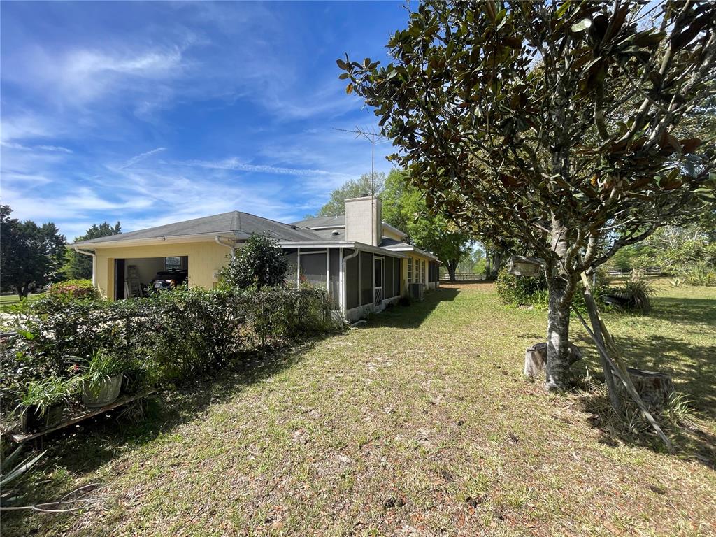 A yellow house with a garage and screened porch sits on a grassy lot — 15121 SE 175TH STREET, WEIRSDALE, FL