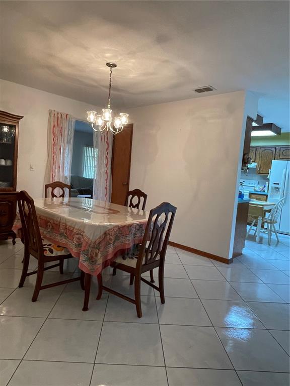 A dining room features a chandelier, a table with a patterned cloth, and tiled floors — 15121 SE 175TH STREET, WEIRSDALE, FL