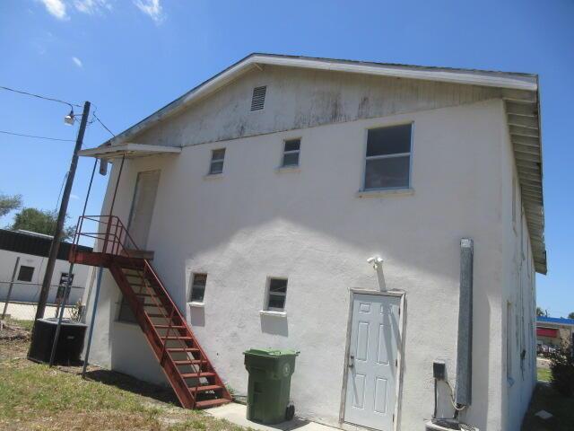 The exterior of a two-story stucco building features a metal staircase and a green trash bin — 1203 1st Street E, Bradenton FL 34208, BRADENTON, FL
