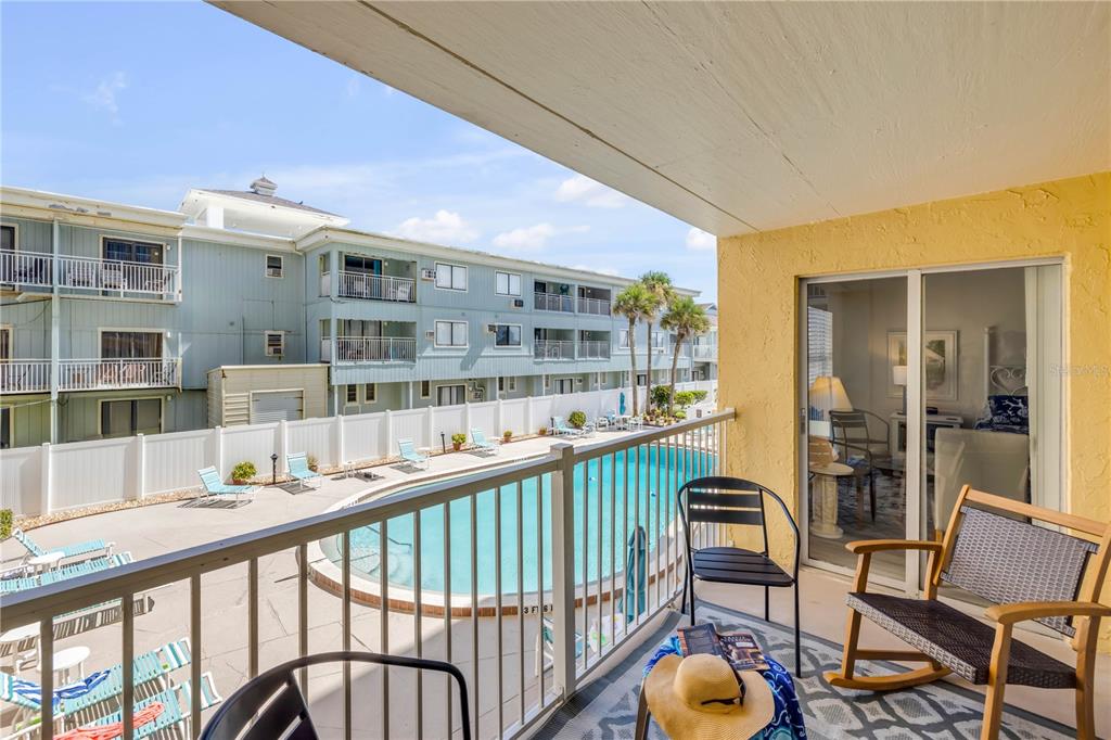 A balcony with outdoor furniture overlooks a swimming pool and a multi-story apartment building — 3501 S ATLANTIC AVENUE UNIT 2060, NEW SMYRNA BEACH, FL