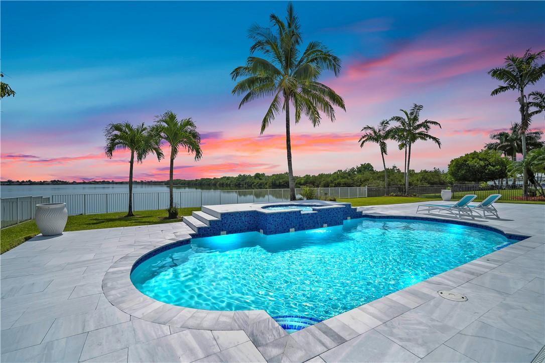 A swimming pool with an attached spa overlooks a lake at sunset with palm trees — 4707 SW 195th Terrace, Miramar FL 33029, MIRAMAR, FL