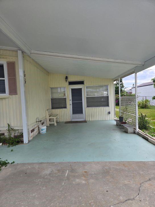 A covered concrete patio area leads to the front door of a yellow mobile home — 1363 SEAGULL DRIVE, ENGLEWOOD, FL