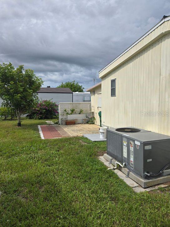 A side view of a mobile home exterior featuring an HVAC unit and a small patio — 1363 SEAGULL DRIVE, ENGLEWOOD, FL