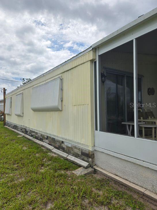 The exterior of a mobile home features yellow metal siding, window awnings, and a screened porch — 1363 SEAGULL DRIVE, ENGLEWOOD, FL