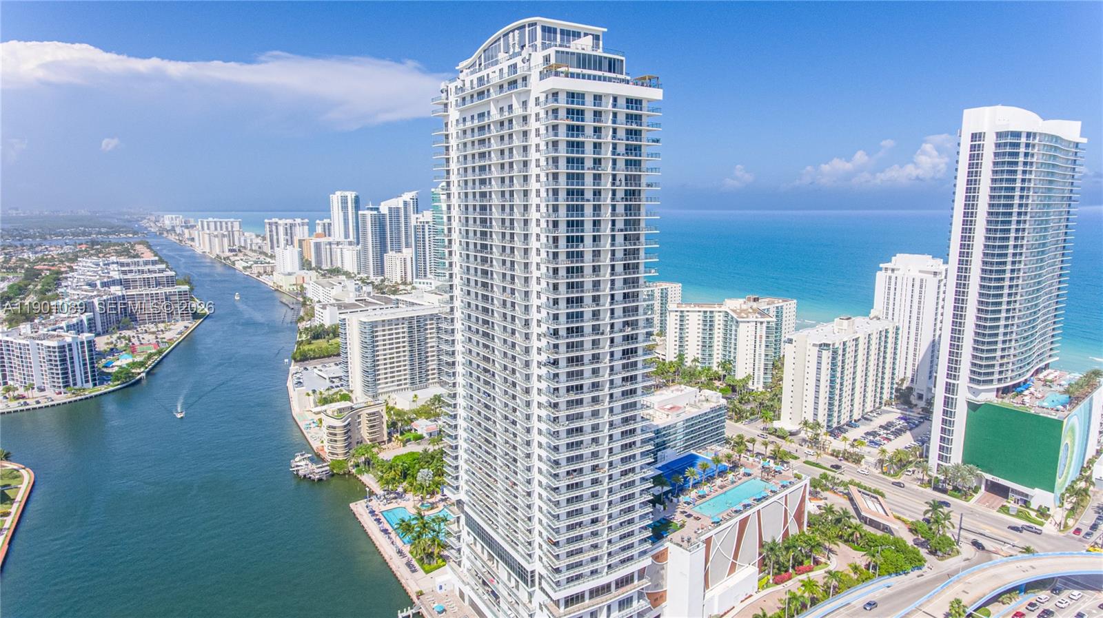 An aerial view shows a tall residential skyscraper situated between a waterway and the ocean — 4010 S Ocean Dr # R1709, Hollywood FL 33019, HOLLYWOOD, FL