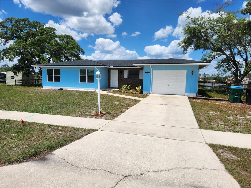 A single-story house with bright blue siding, a white garage door, and a concrete driveway — 1952 ENGLISH DRIVE, DELTONA, FL