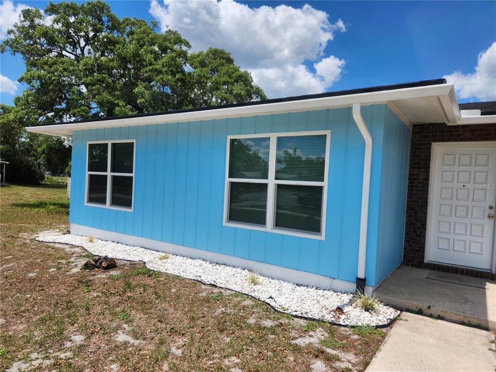 The exterior of a house features light blue vertical siding, white-trimmed windows, and white gravel — 1952 ENGLISH DRIVE, DELTONA, FL
