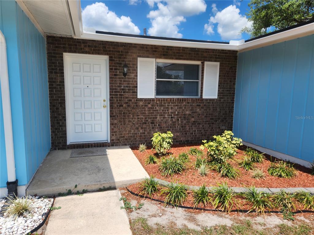 The exterior of a house features a brick facade, a white door, and blue siding — 1952 ENGLISH DRIVE, DELTONA, FL