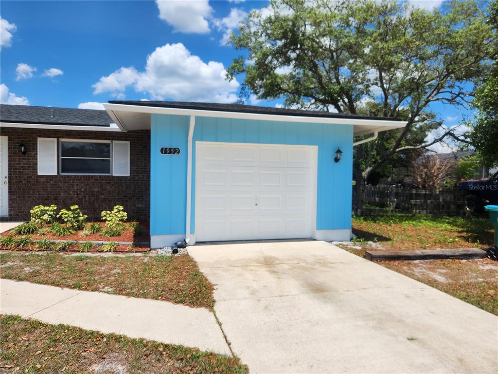 A single-story house features a blue-painted garage, a brick facade, and a concrete driveway — 1952 ENGLISH DRIVE, DELTONA, FL