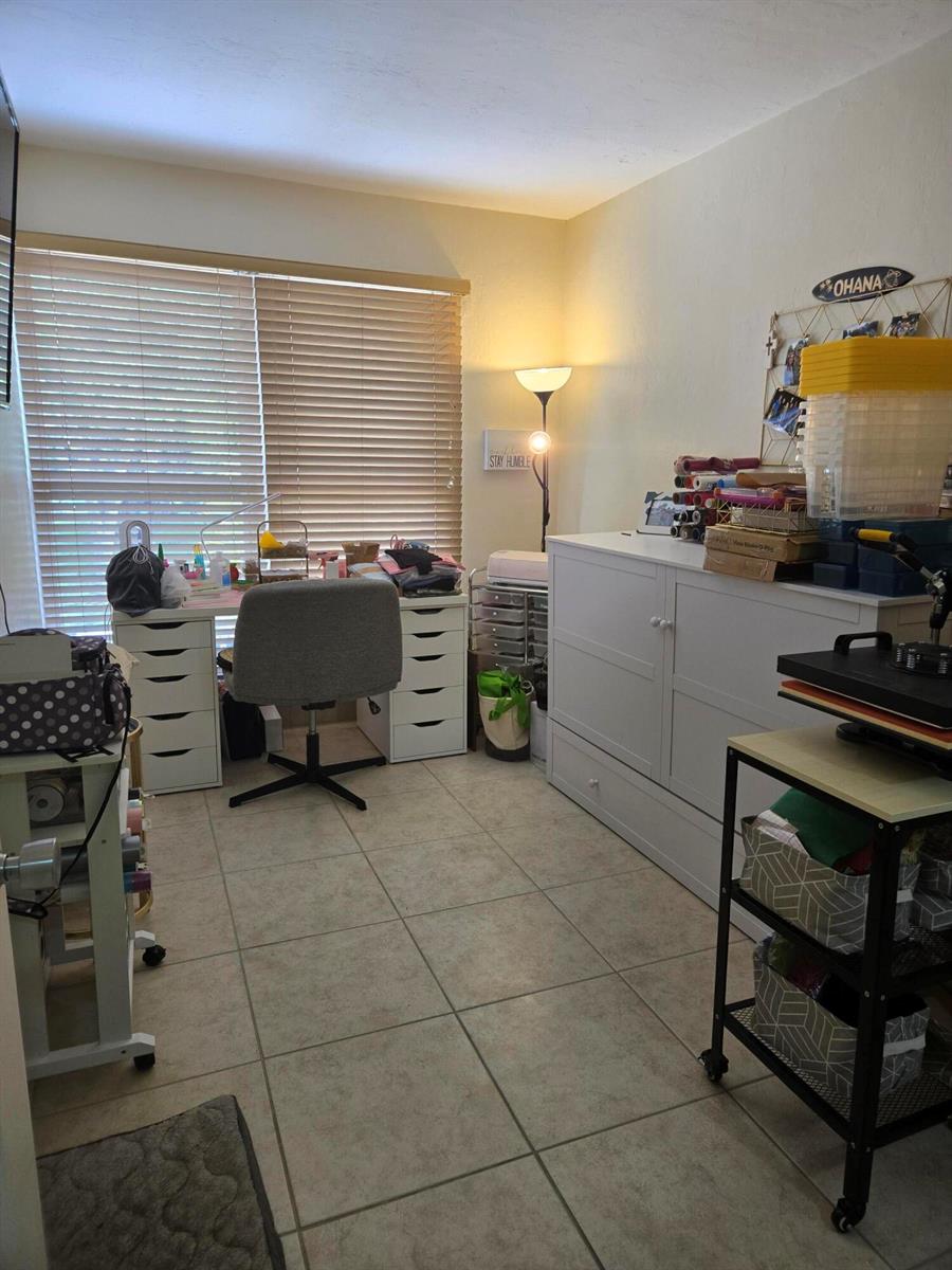 A craft room features a white desk, storage cabinets, tile flooring, and a large window — 8324 SW 103rd Avenue, Miami FL 33173, MIAMI, FL