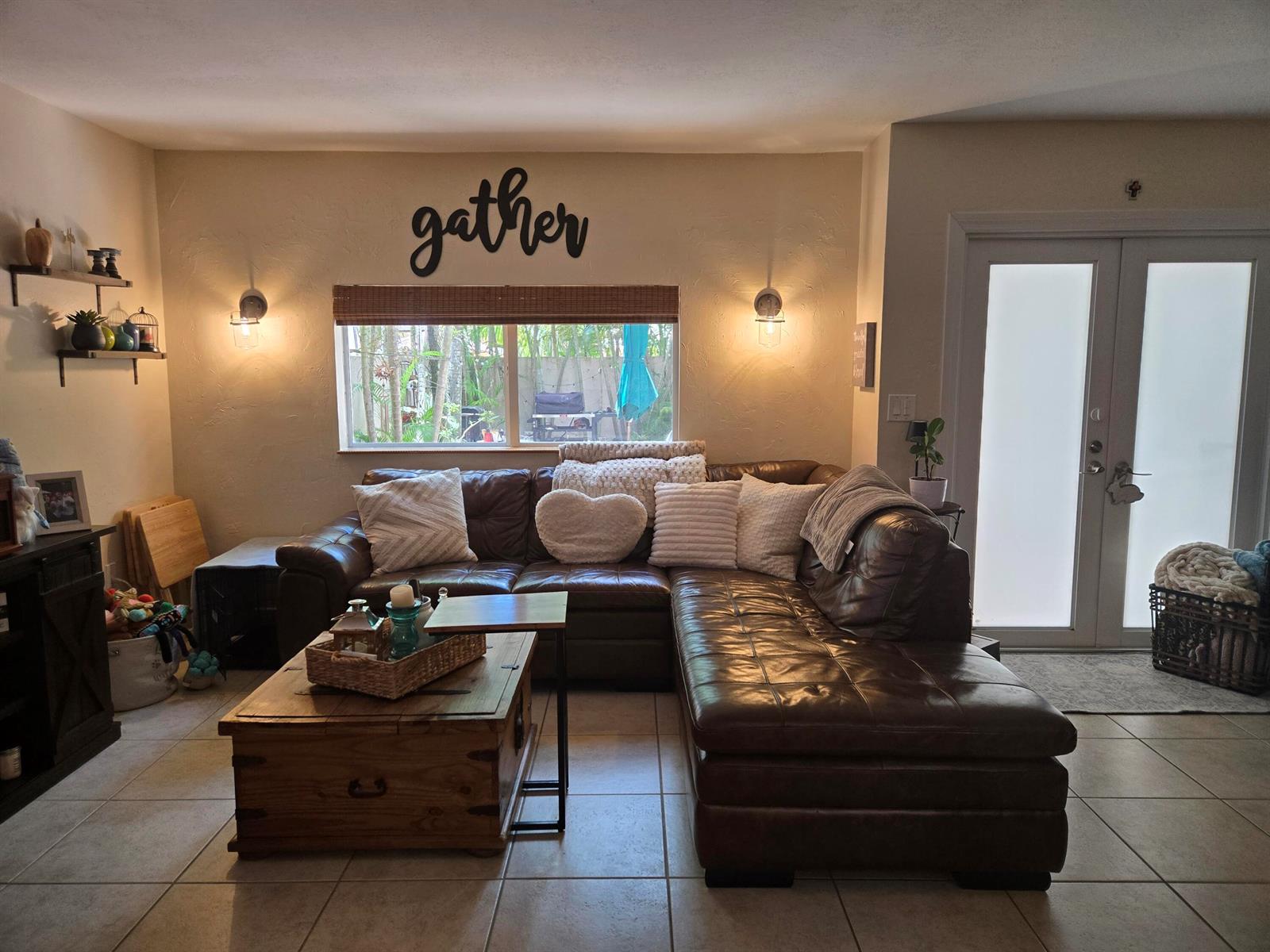 A living room features a brown leather sectional, a wooden coffee table, and wall-mounted sconces — 8324 SW 103rd Avenue, Miami FL 33173, MIAMI, FL